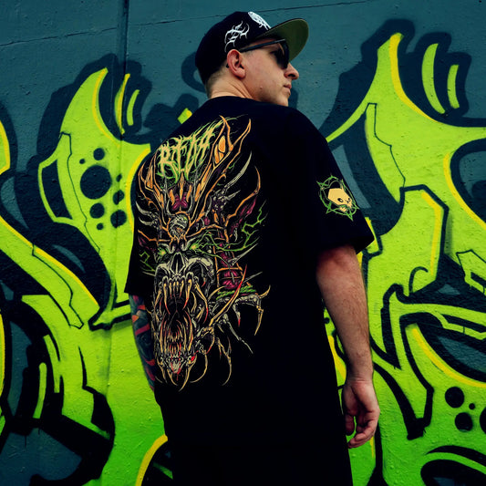 Person wearing a black t-shirt with a colourful dragon design, standing against a vibrant graffiti wall. RTLA-Apparel