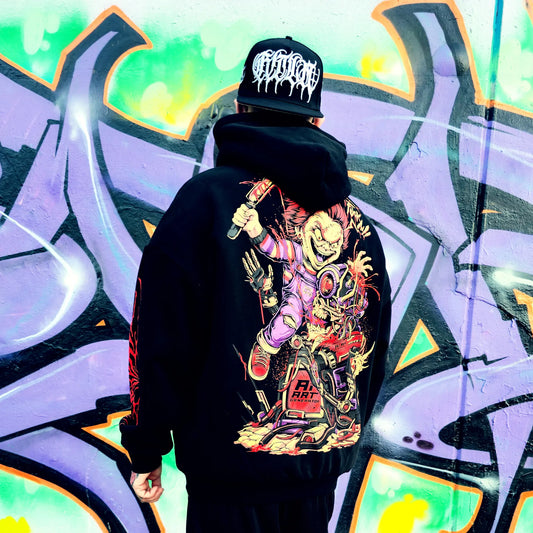 Person wearing a black hoodie with a colorful graphic design, standing in front of a vibrant graffiti wall.