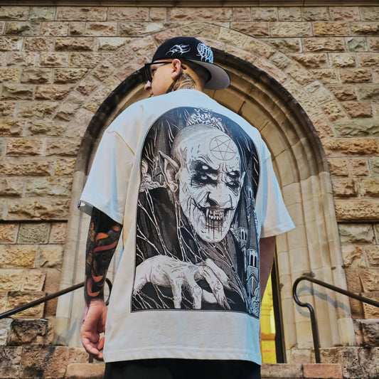 A person wearing a hat and sunglasses faces away from the camera, showcasing an oversized white t-shirt with a large, intricate black and gray graphic of a character with a finger extended. RTLA-Apparel