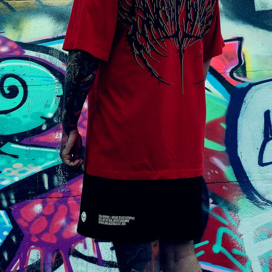 Person wearing a red shirt with black designs against a colorful graffiti wall.