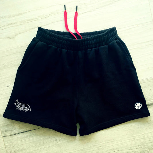 Black shorts with brand logos on a light wooden floor