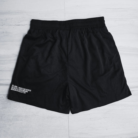 Black shorts with white text on a light gray wooden floor