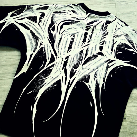 Black t-shirt with white abstract design on a wooden floor