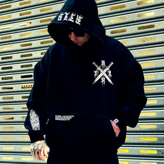 Person wearing a black hoodie with white logo and text, standing in front of a metallic shutter.