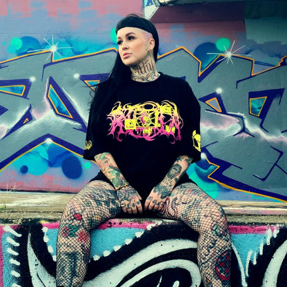 Person with tattoos sitting on a graffiti-covered wall
