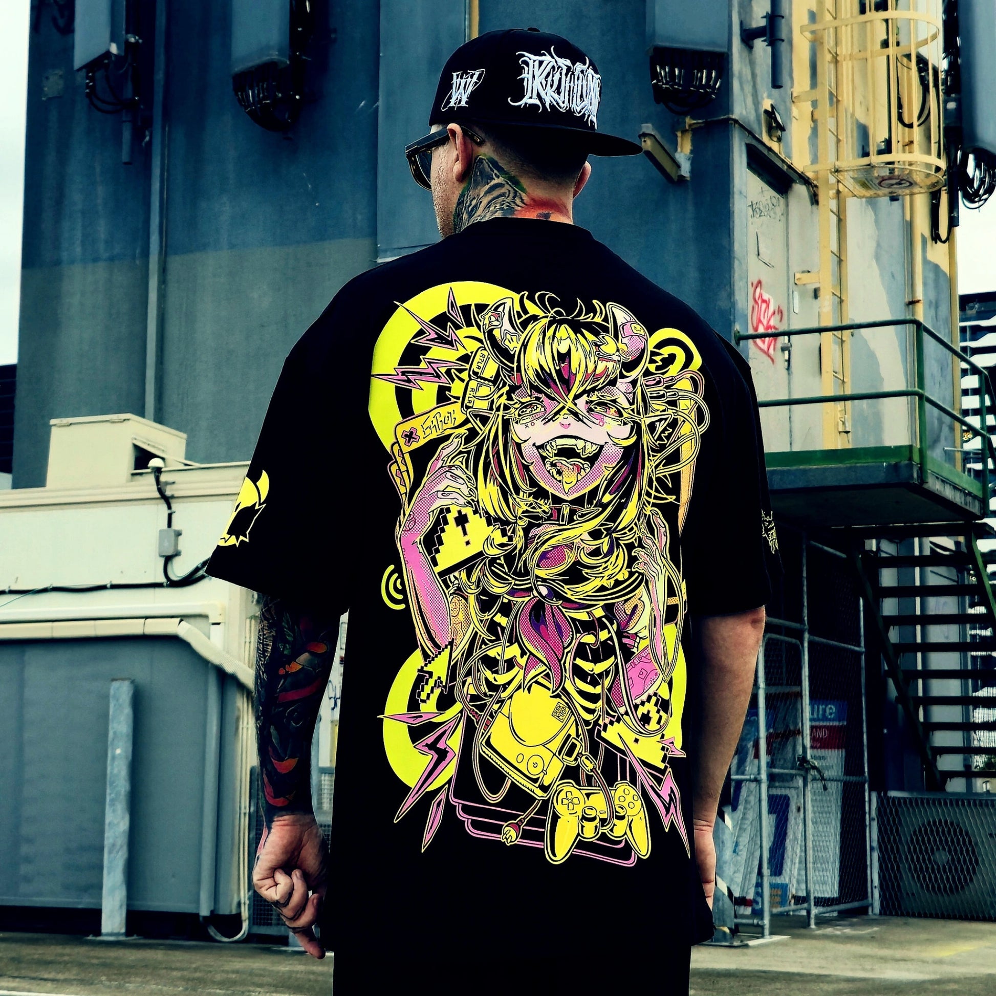 Person wearing a black t-shirt with a colorful graphic design, standing in an urban setting.