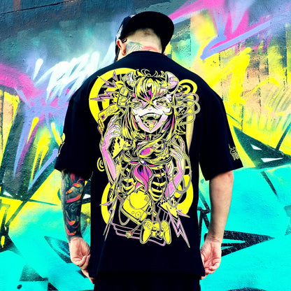 Person wearing a black t-shirt with a colorful graphic design in front of a vibrant graffiti wall.