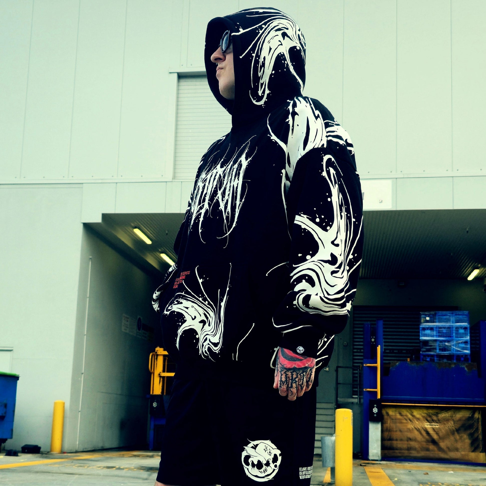 Person wearing a black and white hoodie with graphic designs in an urban setting