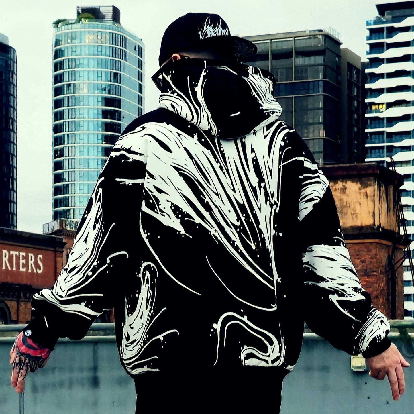 Person wearing a black and white jacket with a cityscape background