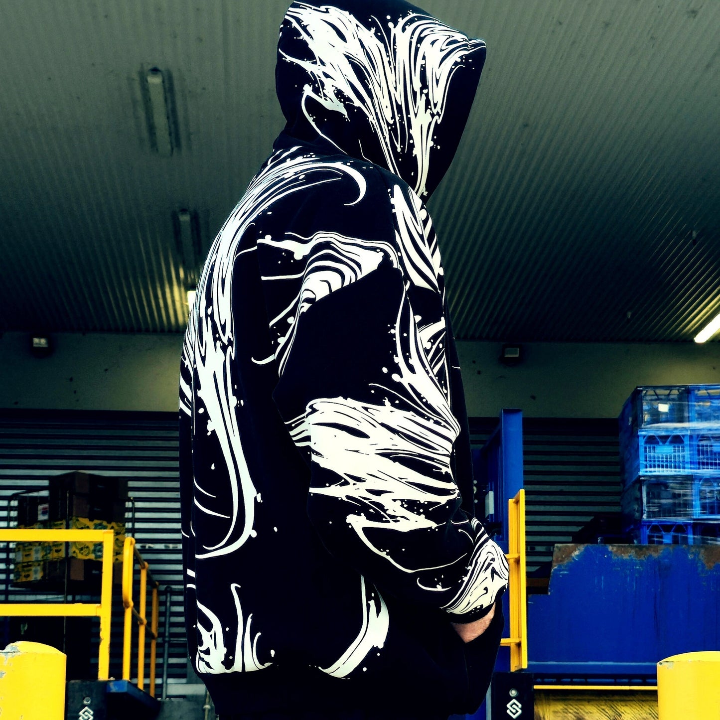 Person wearing a black hoodie with white abstract designs in an indoor setting.