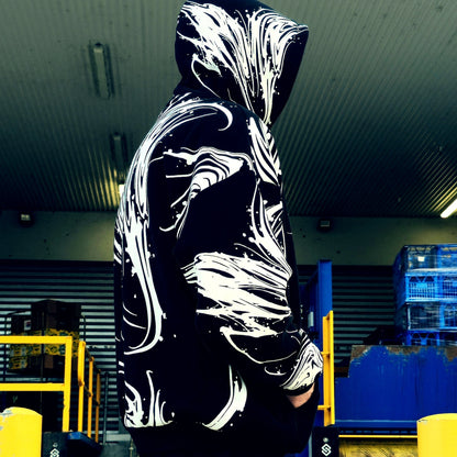 Person wearing a black hoodie with white abstract designs in an indoor setting.