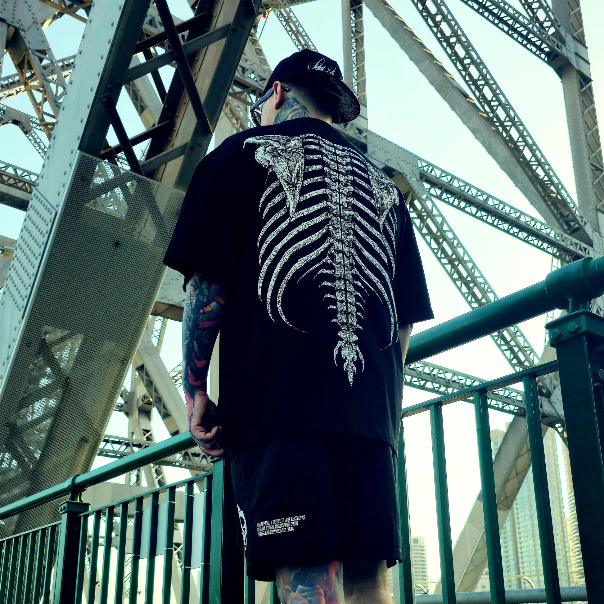 Person wearing a black t-shirt with a skeleton design on a bridge