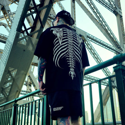 Person wearing a black t-shirt with a skeleton design on a bridge