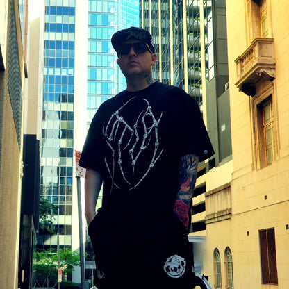 Person wearing a black t-shirt with white graphic design in an urban setting