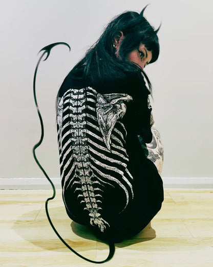 Person with a detailed back tattoo of a skeleton on a plain background