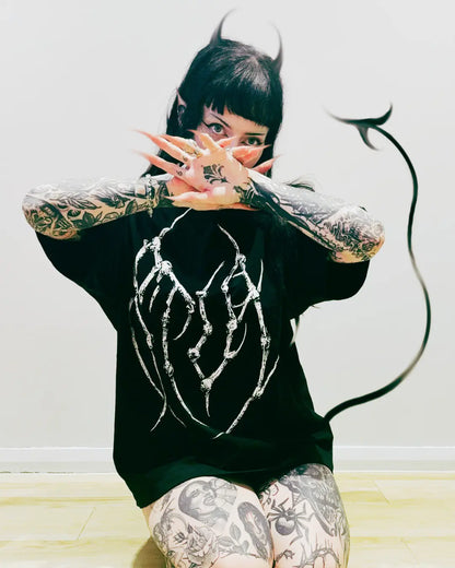 Person wearing a black oversized t-shirt with a white design, standing against a plain background.