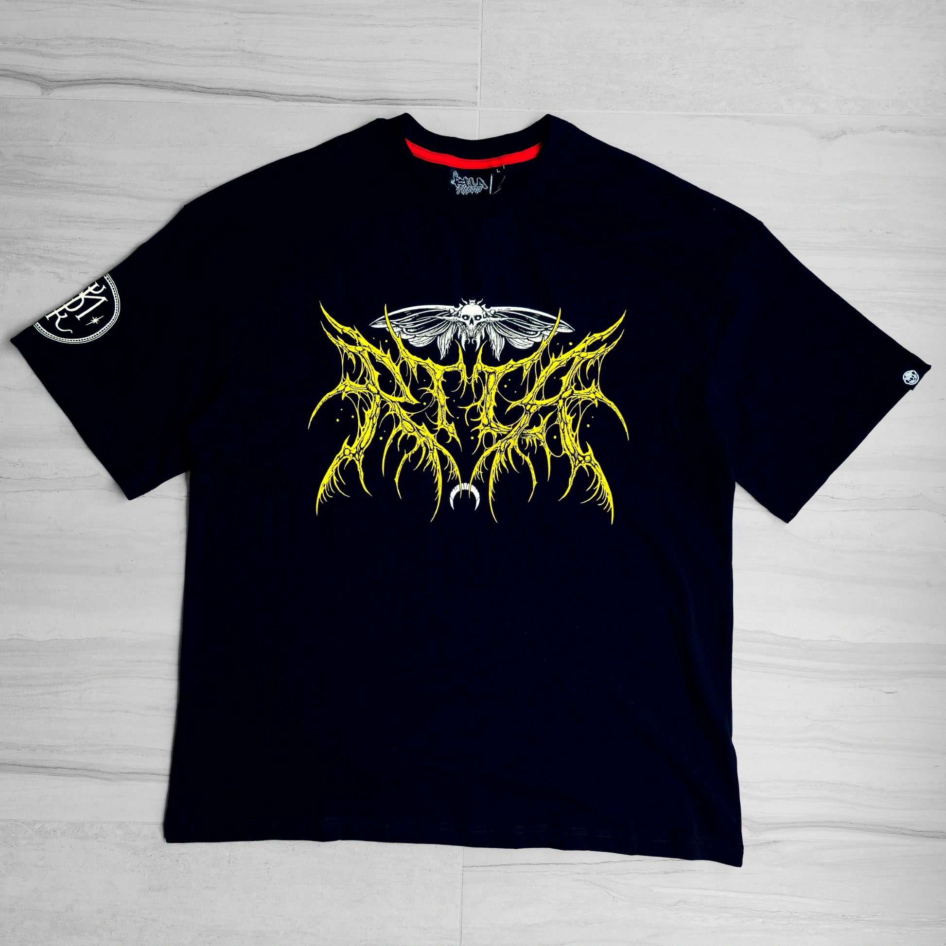 Black t-shirt with yellow and white graphic design on a light gray surface