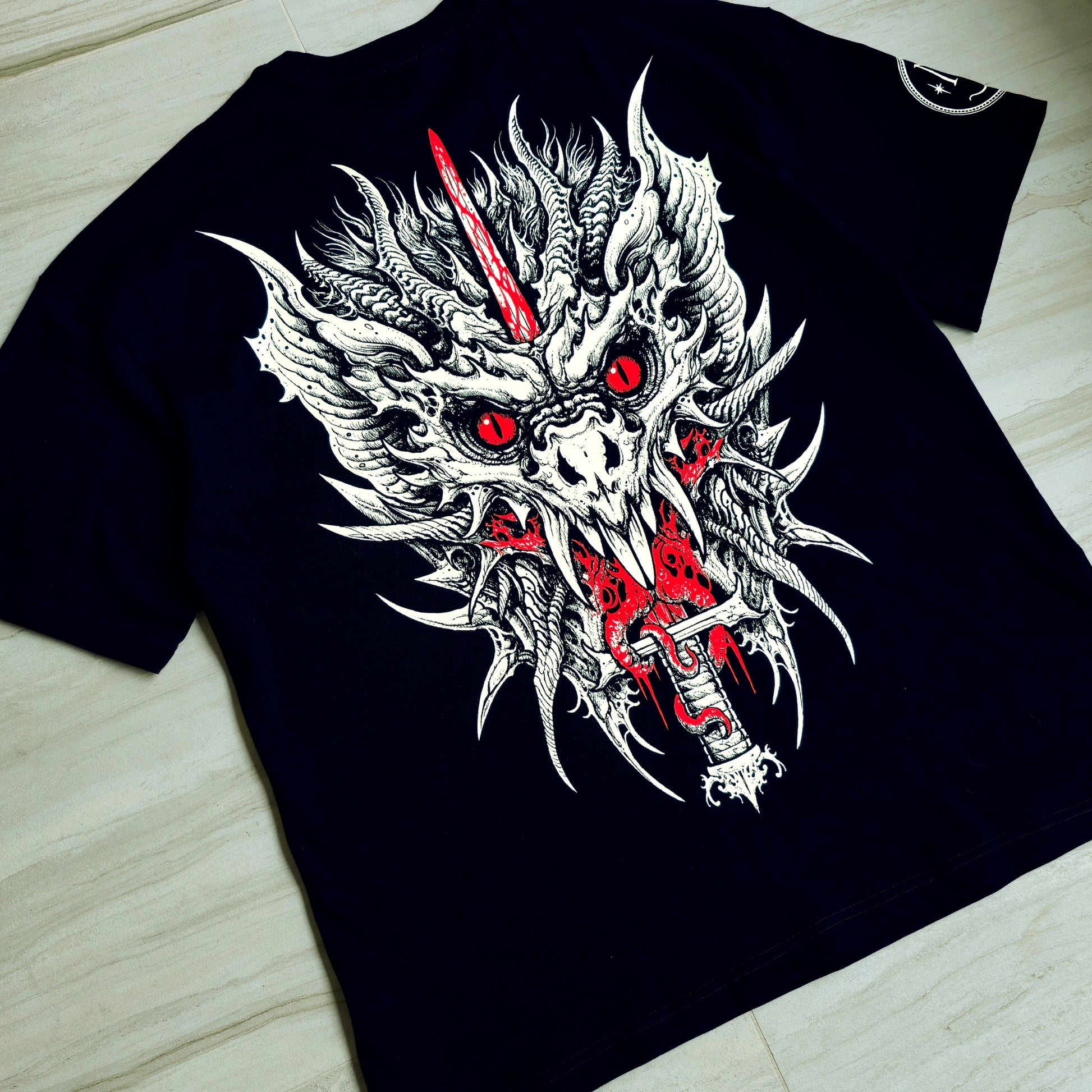 Black t-shirt with a dragon graphic design featuring red accents on a wooden surface.