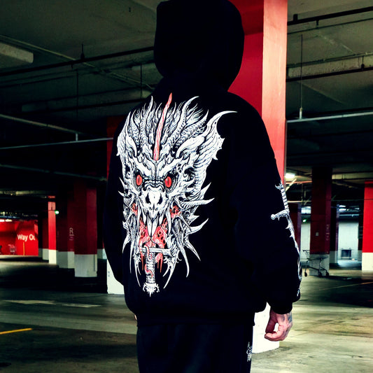 A person viewed from behind wearing a black hoodie in a parking garage, featuring a large white and red dragon graphic printed across the back.