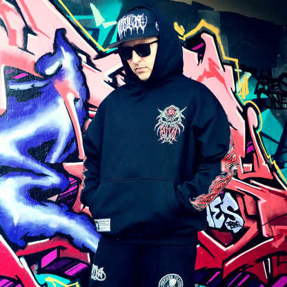 Person wearing a black hoodie with a logo in front of colourful graffiti art. RTLA-Apparel