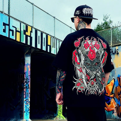 Person wearing a black t-shirt with a detailed graphic design, standing in front of a colorful mural.