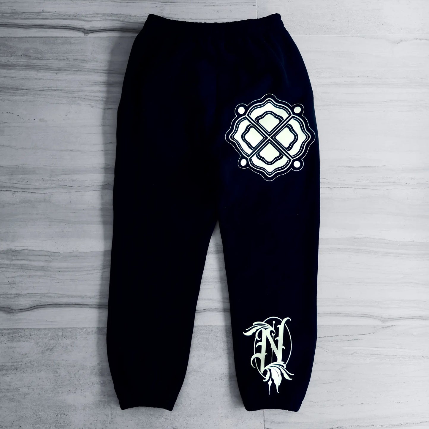 Black sweatpants with white logo on a gray wooden surface
