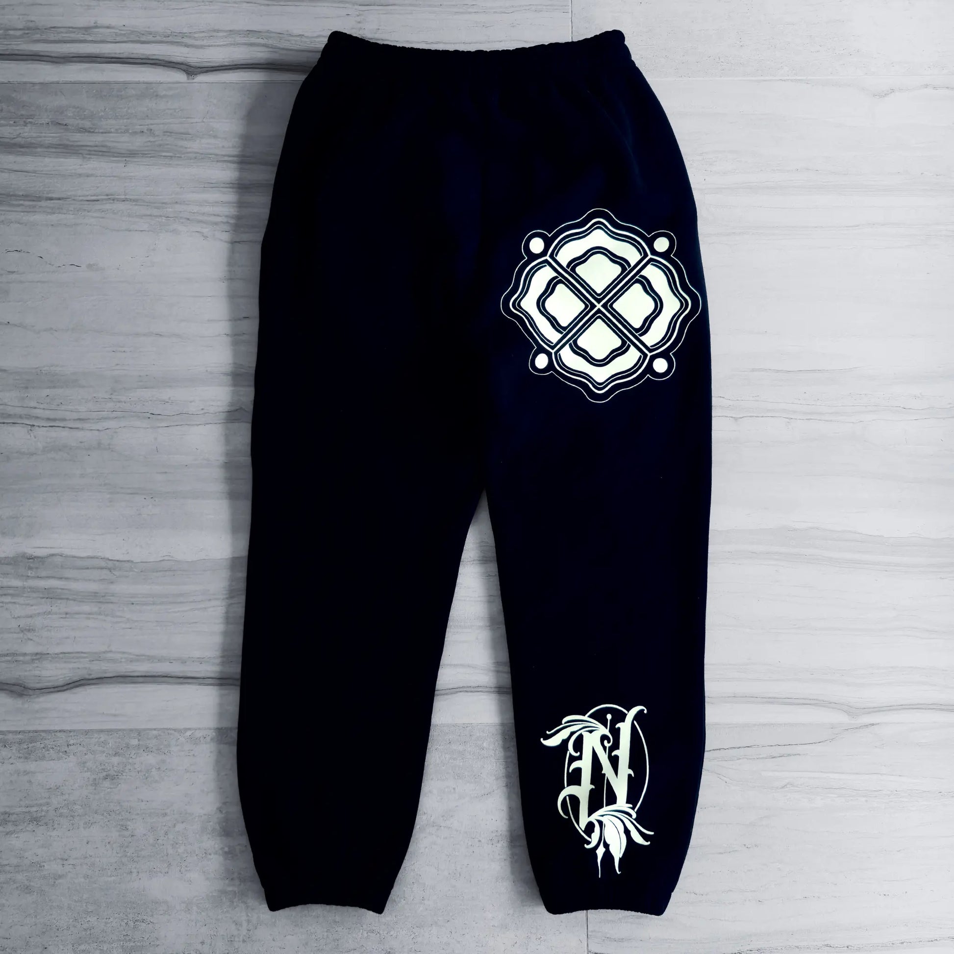 Black sweatpants with white logo on a gray wooden surface
