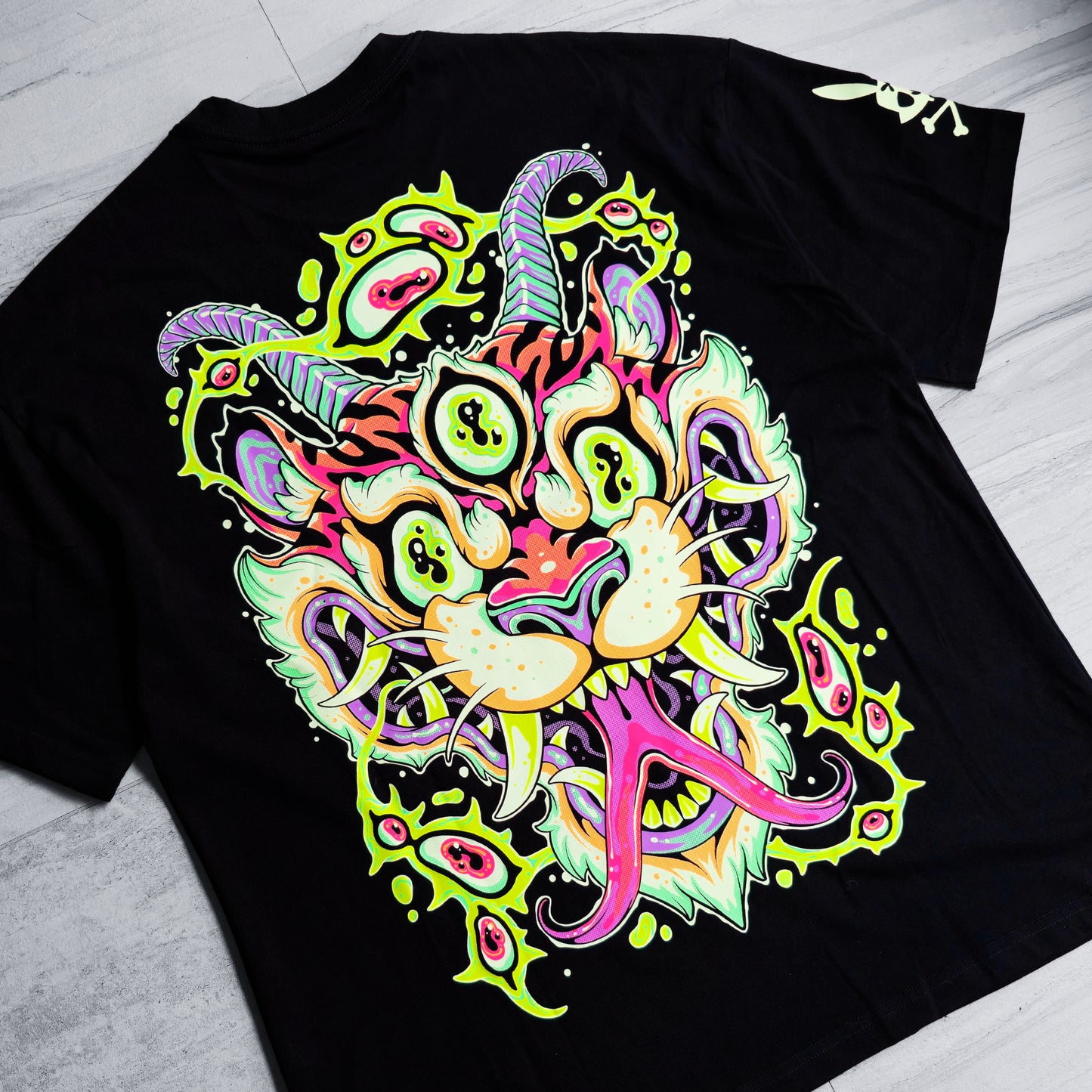 Black t-shirt with a colorful, abstract design on a light gray surface