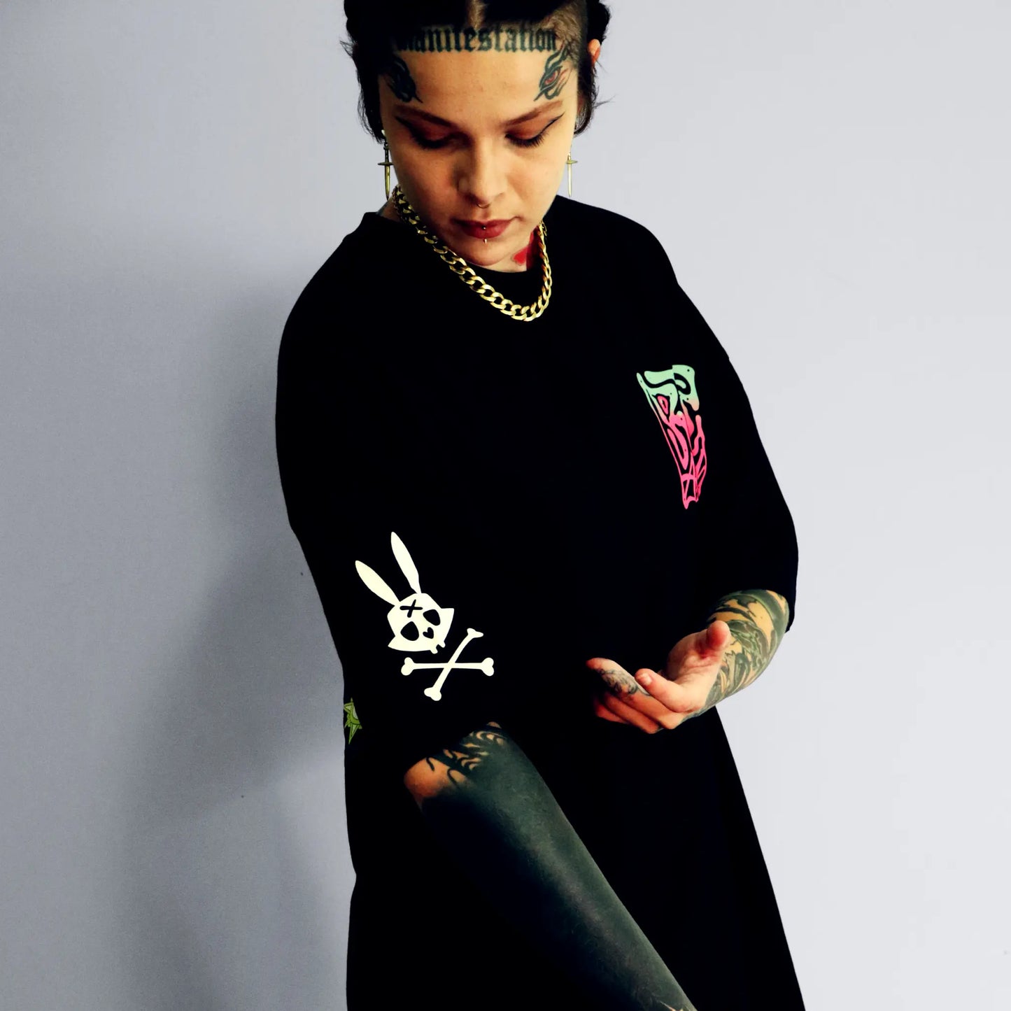 Person wearing a black sweatshirt with graphic designs on a plain background