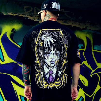 Person wearing a black t-shirt with a graphic design of a woman's face and text, standing in front of a colorful graffiti wall.