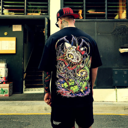 Man wearing a black t-shirt with a colorful graphic design, standing in front of a building entrance.