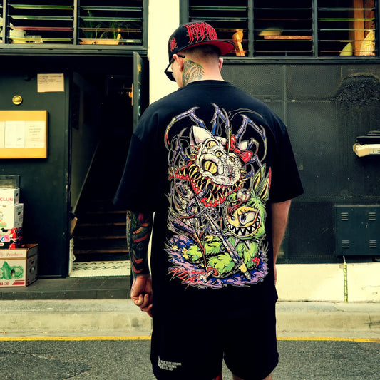 Man wearing a black t-shirt with a colorful graphic design, standing in front of a building entrance.