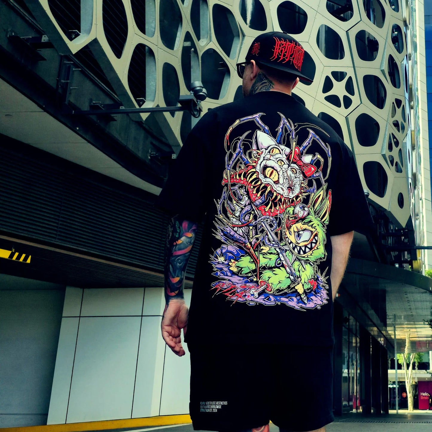 Person wearing a black t-shirt with a colorful dragon design outdoors.