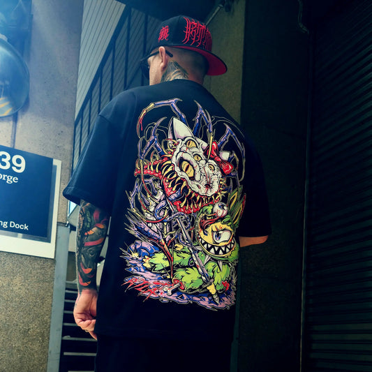 Person wearing a black t-shirt with a colorful graphic design on the back, standing in an urban setting.
