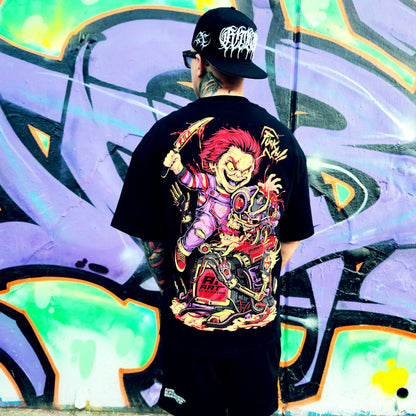 Person wearing a black t-shirt with a colorful graphic design in front of a graffiti wall.