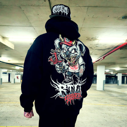 Person wearing a black hoodie with a graphic design on the back in an indoor parking garage.