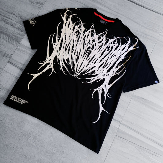 Black t-shirt with white abstract design on a gray floor