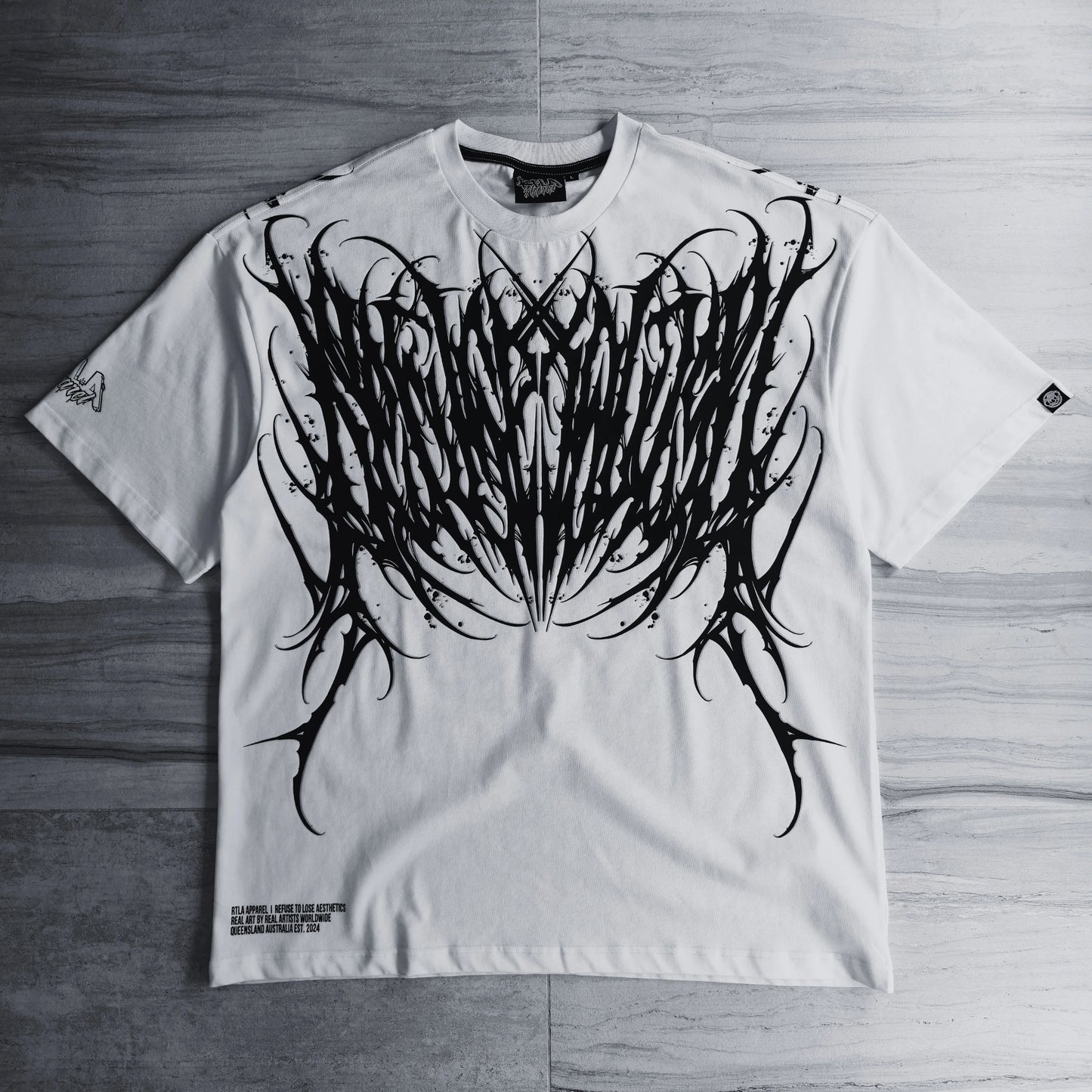 White t-shirt with black tribal design on a wooden surface