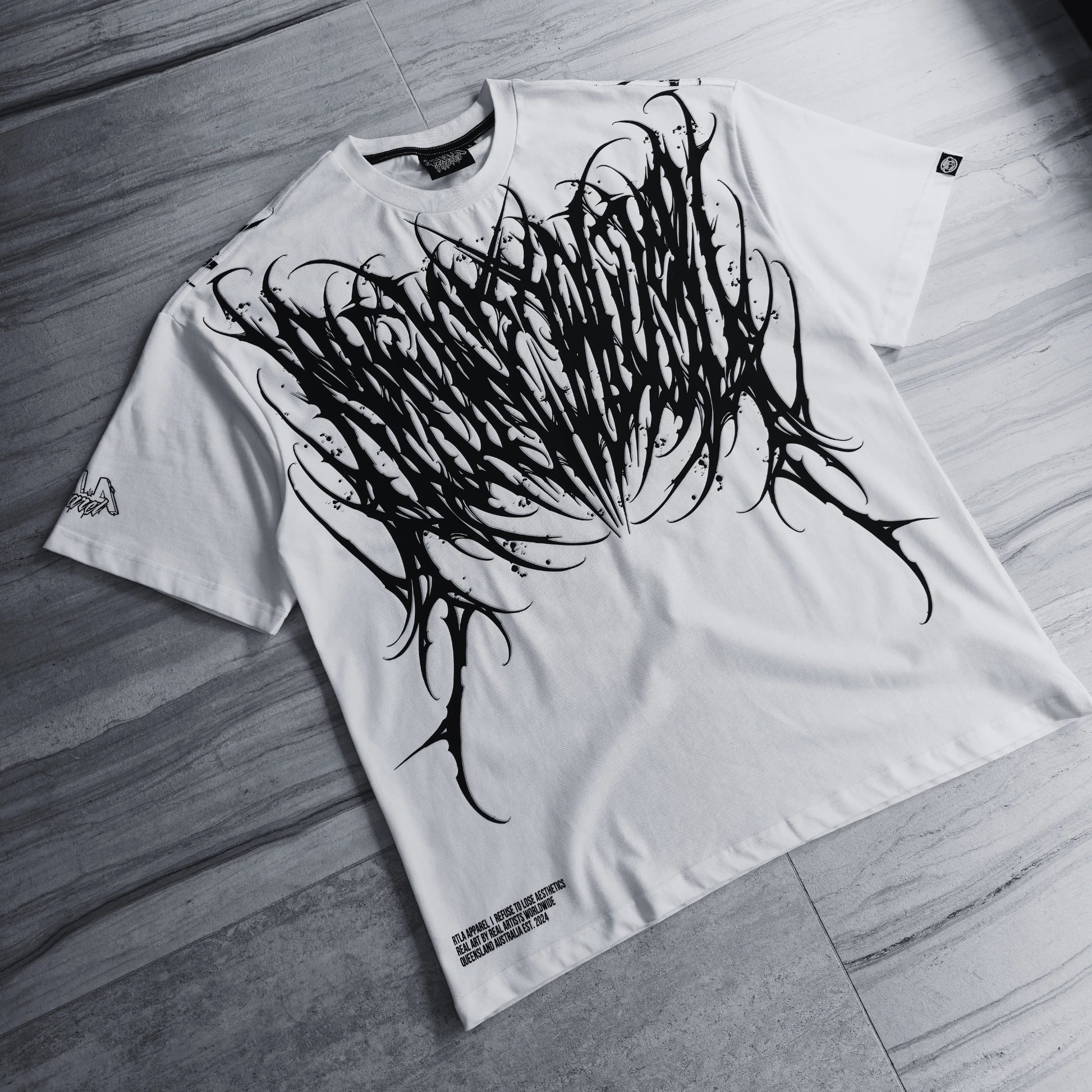 White t-shirt with black abstract design on a wooden floor