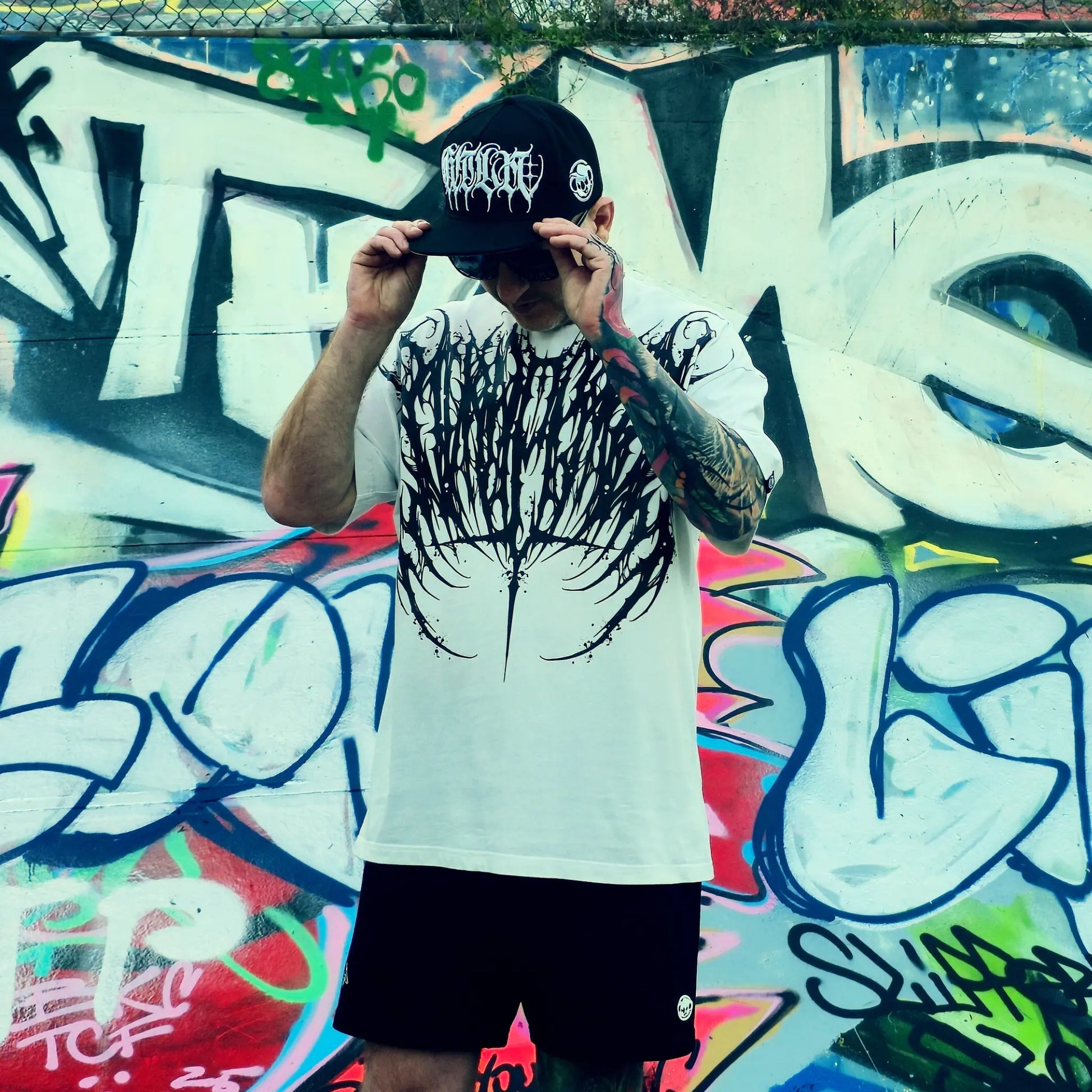 Person wearing a white t-shirt with black graphic design, front and back views, against a dark background.