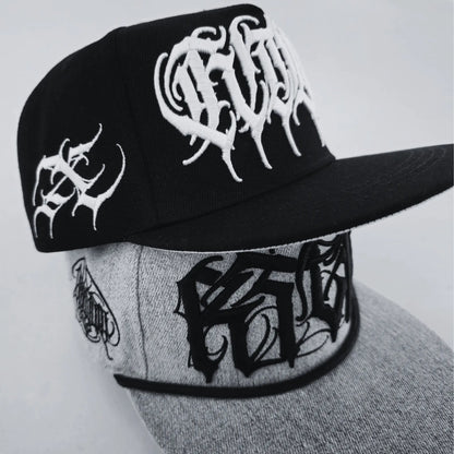 Two baseball caps with text patterns, one in black and the other in grey, both with stylized text designs. RTLA-Apparel