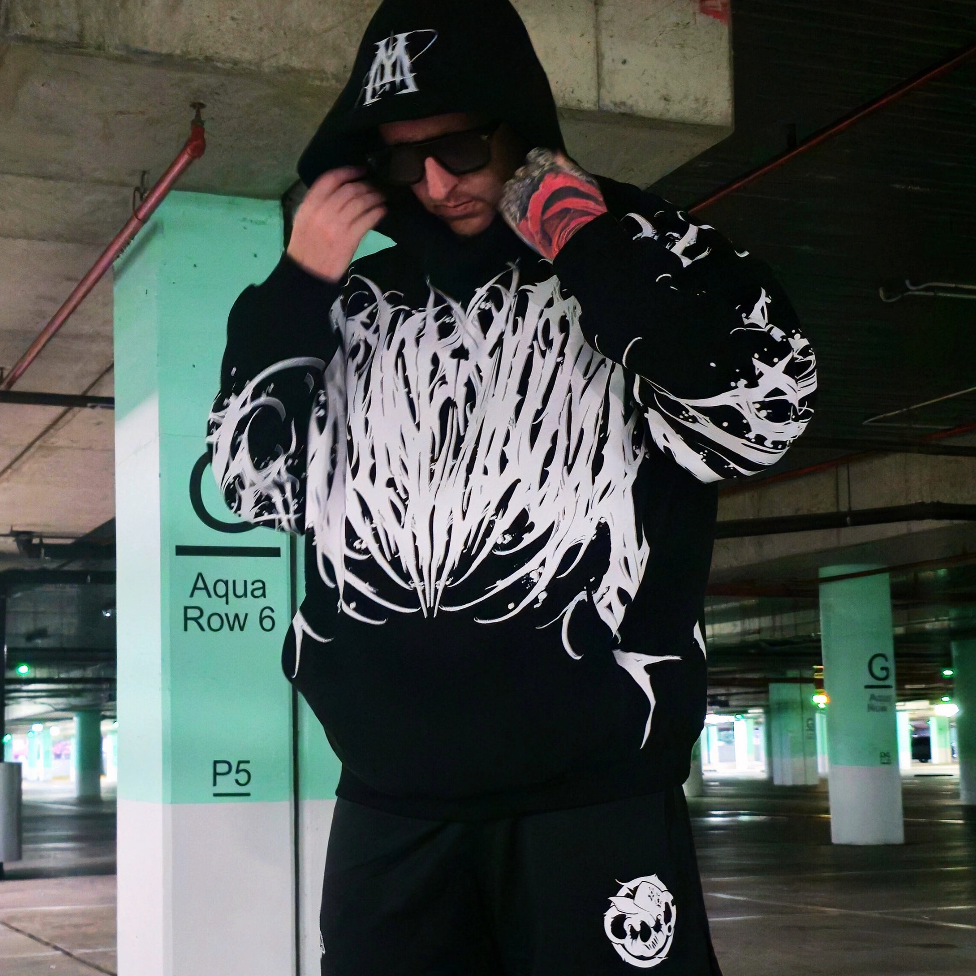 Person wearing a black hoodie with white designs in an urban setting