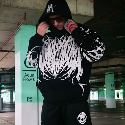Person wearing a black hoodie with white designs in an urban setting