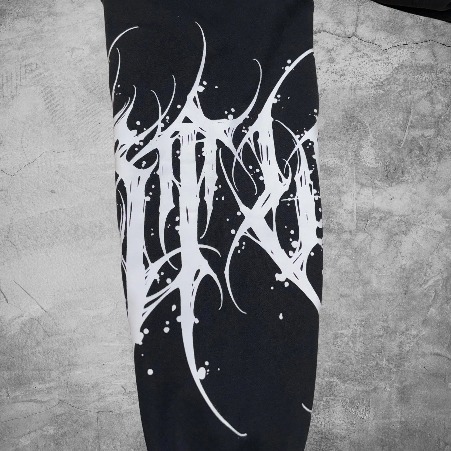 Black leggings with white abstract design on a textured gray surface