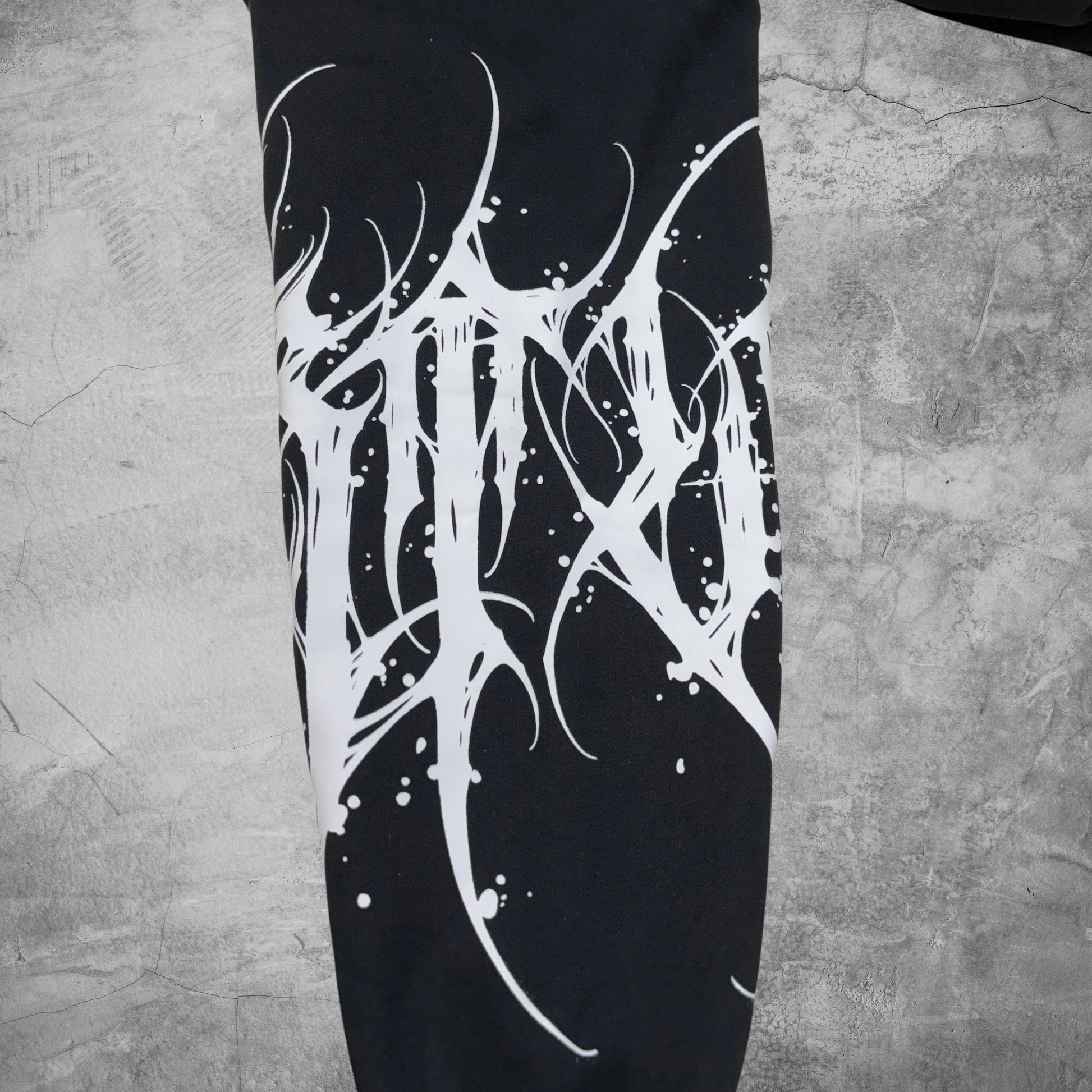 Black leggings with white abstract design on a textured gray surface