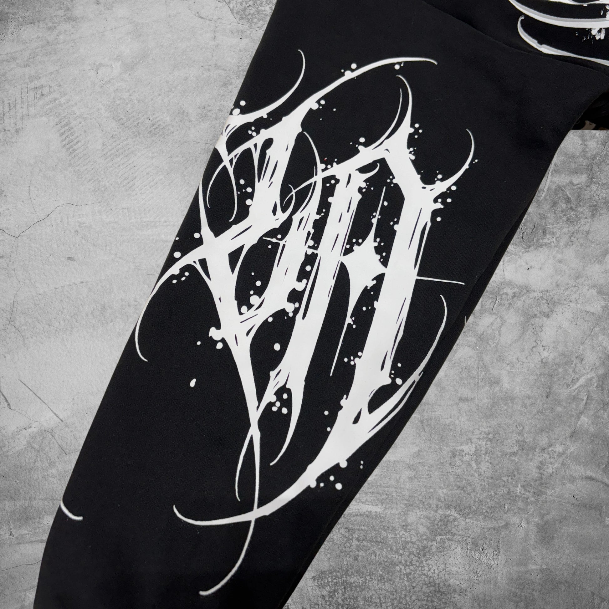 Black pants with white abstract design on a textured gray background