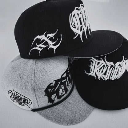 Three caps in black and grey with white logo on a light background. RTLA-Apparel