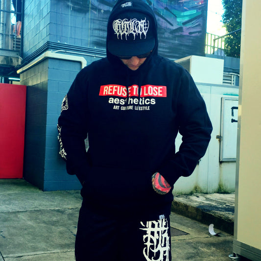 Person wearing a black hoodie with text and a cap in an urban setting