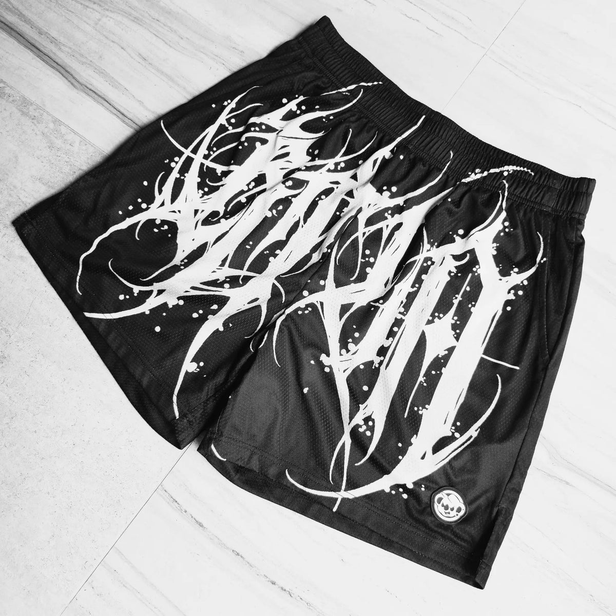 Black shorts with white graphic design on a light gray floor