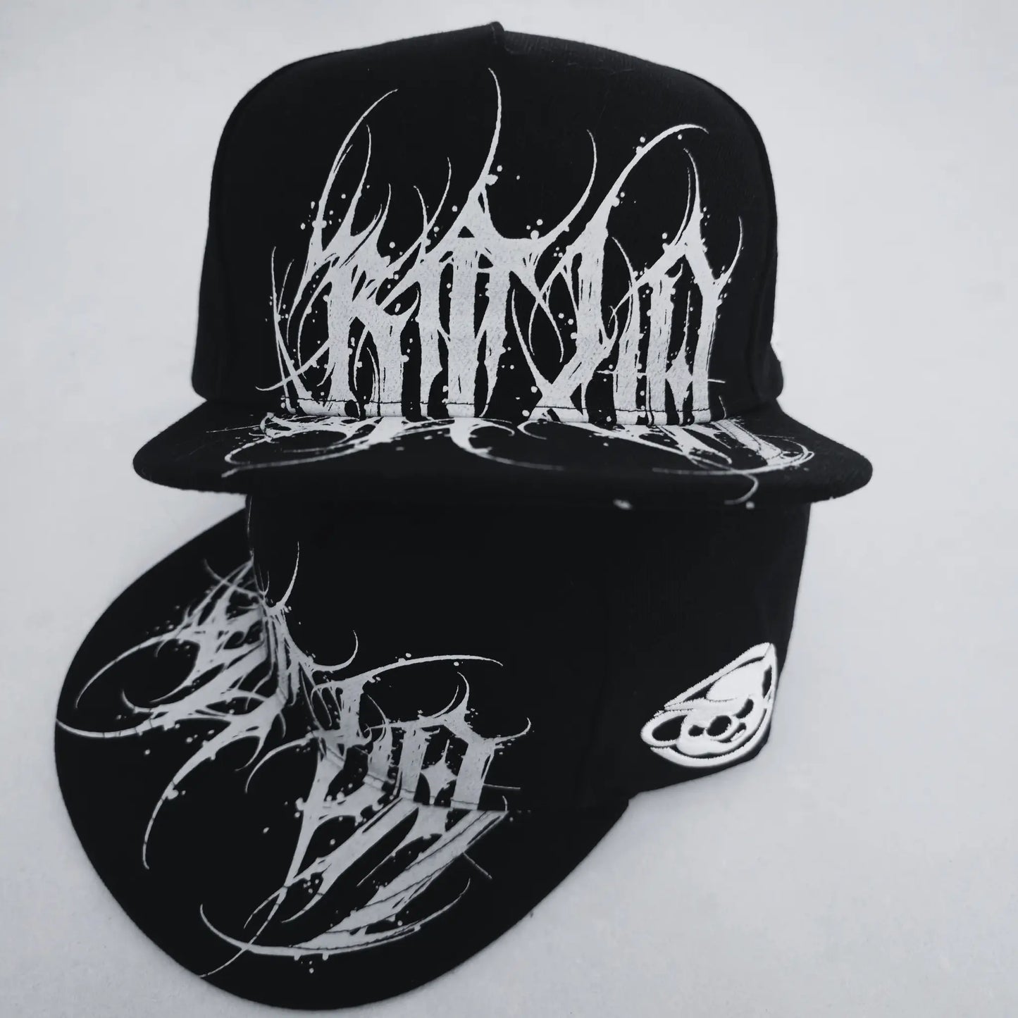 Black cap with white abstract designs on a light gray background